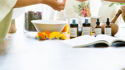 Two women working together to create a blend of essential oils in a glass container.